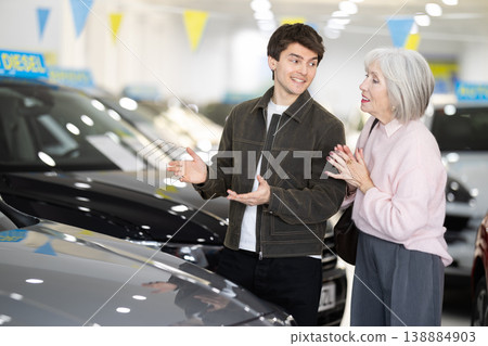 Adult son helps her elderly mother choose a new car at car dealership 138884903