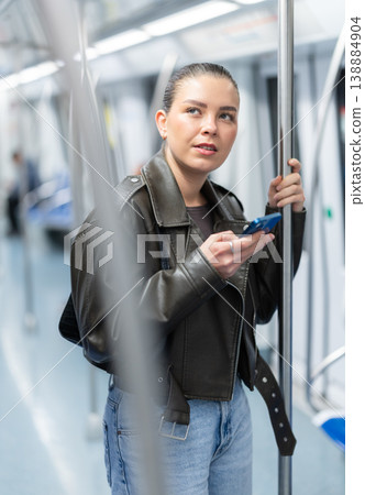 Girl stands in subway car and writes message on her smartphone screen Girl stands in subway car and writes message on her smartphone screen 138884904