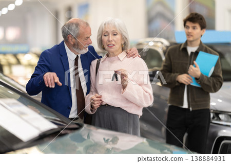 Elderly couple with new car keys, salesman with contract 138884931
