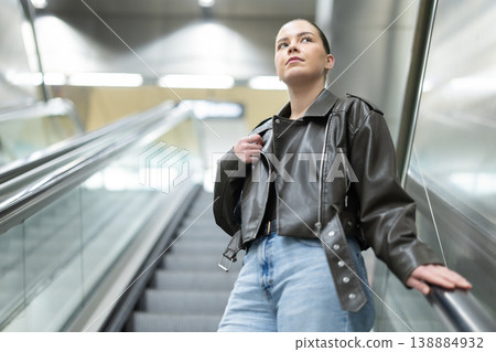Young woman riding escalator up in subway station Young woman riding escalator up in subway station 138884932