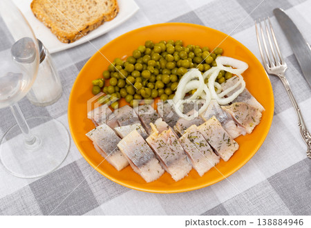 Tasty slices herring fish with canned green peas decorated by onion rings Tasty slices herring fish with canned green peas decorated by onion rings 138884946
