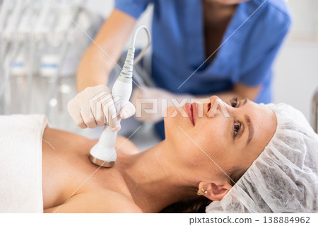 Young woman undergoing ultrasound cosmetic treatment on chest and neck area Young woman undergoing ultrasound cosmetic treatment on chest and neck area 138884962