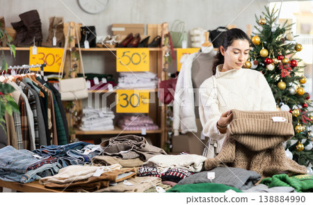 Armenian girl near showcase pick out and buying sweater, New Year eve 138884990