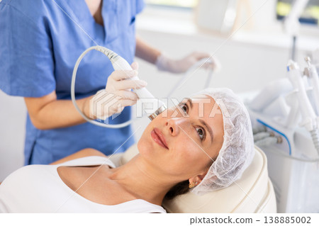 Young woman undergoing cosmetic high frequency ultrasound facial treatment 138885002