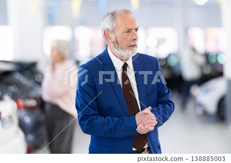 Elderly successful car salesman offers to buy a car at car dealership 138885003