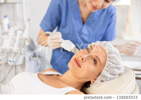 Young woman undergoing facial cleansing procedure using ultrasonic shovel Young woman undergoing facial cleansing procedure using ultrasonic shovel 138885033