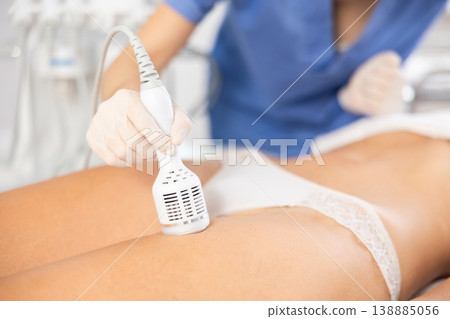 Aesthetician performing cryotherapy using cooling attachment on female client thighs Aesthetician performing cryotherapy using cooling attachment on female client thighs 138885056