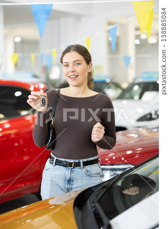 Happy cheerful girl bought car - portrait of joyful girl with car keys in car dealership Happy cheerful girl bought car - portrait of joyful girl with car keys in car dealership 138885084
