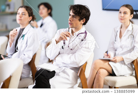 Young female doctor listening and taking notes in lecture hall Young female doctor listening and taking notes in lecture hall 138885099