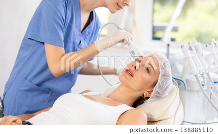Young woman cosmetologist doing whitening procedure to young woman Young woman cosmetologist doing whitening procedure to young woman 138885110