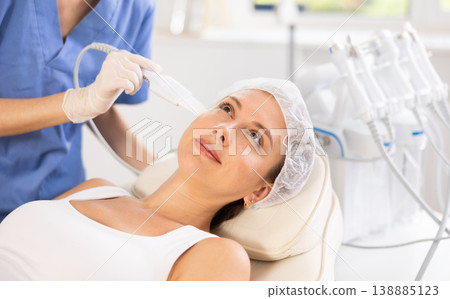 Young woman undergoing facial cleansing procedure using ultrasonic shovel Young woman undergoing facial cleansing procedure using ultrasonic shovel 138885123