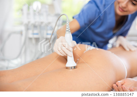 Cosmetologist performing high-frequency ultrasound procedure on female buttocks Cosmetologist performing high-frequency ultrasound procedure on female buttocks 138885147
