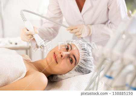 Young woman cosmetologist doing moisturizing procedure to young woman Young woman cosmetologist doing moisturizing procedure to young woman 138885150