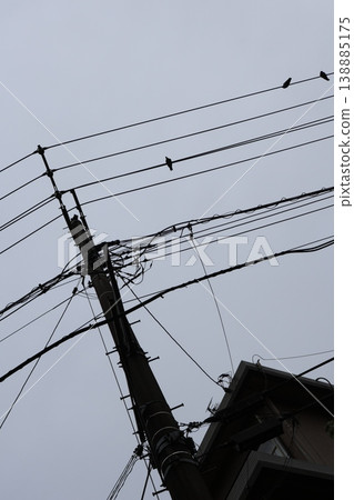 A scene from a Japanese residential area on a cloudy day, with utility poles and a complex network of power lines. A scene from a Japanese residential area on a cloudy day, with utility poles and a complex network of power lines. 138885175