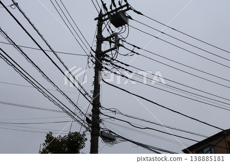 A scene from a Japanese residential area on a cloudy day, with utility poles and a complex network of power lines. A scene from a Japanese residential area on a cloudy day, with utility poles and a complex network of power lines. 138885181