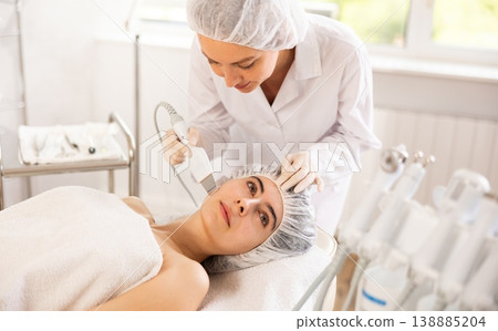 Young woman cosmetologist doing exfoliation procedure to young woman Young woman cosmetologist doing exfoliation procedure to young woman 138885204