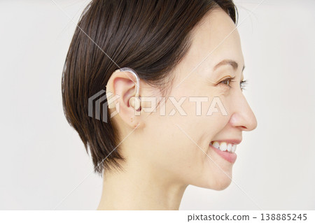 40 多歲女性使用助聽器，白色背景 138885245