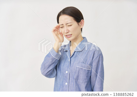 Woman in pajamas with headache on white background 138885262