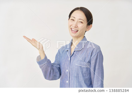 一位身穿睡衣的女士，手掌放在白色背景上，指向左側 138885284