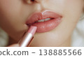 A close-up of a woman's beautiful lips as she carefully applies lipstick during her makeup routine before going out. 138885566