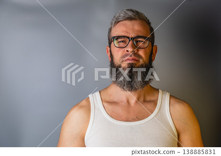 Man with glasses and beard stands against a gray background Man with glasses and beard stands against a gray background 138885831