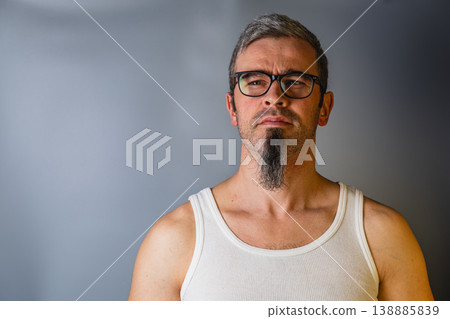Man with gray hair and glasses poses against a plain background Man with gray hair and glasses poses against a plain background 138885839