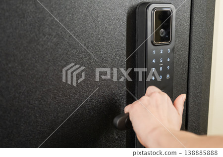 A woman opens a modern smart door lock with a digital keypad and biometric fingerprint access. 138885888