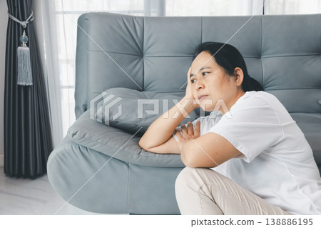 Sad depressed woman leaning on gray sofa by window at home, head in hand. Mental health anxiety, stress, burnout and loneliness concept for therapy, counseling, support and awareness. sad, anxious Sad depressed woman leaning on gray sofa by window at home, head in hand. Mental health anxiety, stress, burnout and loneliness concept for therapy, counseling, support and awareness. sad, anxious 138886195