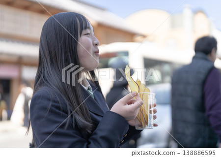 Female students in school uniforms enjoying the local specialty, sweet potato chips. 138886595