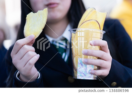 一名身穿制服的女學生正在享用當地特色美食－地瓜片（未露出臉部）。 138886596