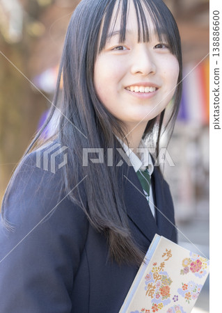 一位笑容燦爛的高中女生在寺廟參拜時手持集章簿。學校旅行、家庭旅行、日本文化。 一位笑容燦爛的高中女生在寺廟參拜時手持集章簿。學校旅行、家庭旅行、日本文化。 138886600