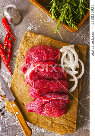 Juicy raw piece of selected veal with spices and herbs, on a stone background. Veal, steak. Top view. Juicy raw piece of selected veal with spices and herbs, on a stone background. Veal, steak. Top view. 138886923