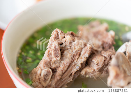 Hot and spicy pork bone soup with herbs and clear broth Thai tom saep featuring tender meat and rich flavor traditional comfort food with fresh green garnish closeup detail Hot and spicy pork bone soup with herbs and clear broth Thai tom saep featuring tender meat and rich flavor traditional comfort food with fresh green garnish closeup detail 138887281