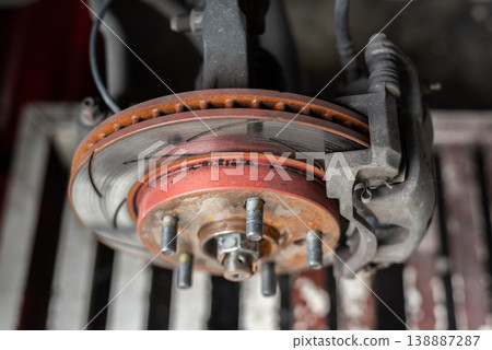 Closeup of car brake disc rotor and caliper showing wear rust and mechanical detail in garage environment highlighting maintenance safety and automotive repair concept Closeup of car brake disc rotor and caliper showing wear rust and mechanical detail in garage environment highlighting maintenance safety and automotive repair concept 138887287