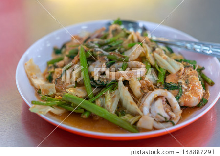 Thai seafood sukiyaki dry stir fry with squid shrimp vegetables and glass noodles in rich sauce served on plate showing fresh ingredients and bold flavor popular street food closeup Thai seafood sukiyaki dry stir fry with squid shrimp vegetables and glass noodles in rich sauce served on plate showing fresh ingredients and bold flavor popular street food closeup 138887291