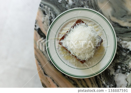 Fresh bread butter toast with Vanilla flavor ice cream topped with grated Parmesan cheese on white ceramic plate on marble table. Fresh bread butter toast with Vanilla flavor ice cream topped with grated Parmesan cheese on white ceramic plate on marble table. 138887591