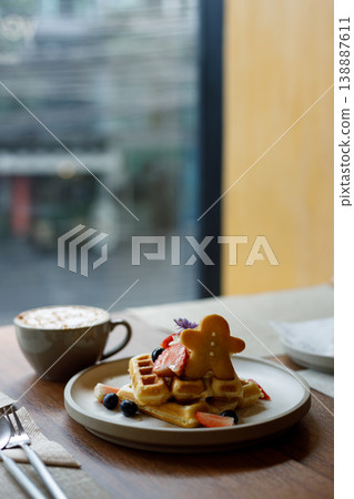 Cup of hot milk caramel macchiato coffee and plate of waffles on table by the window. 138887611
