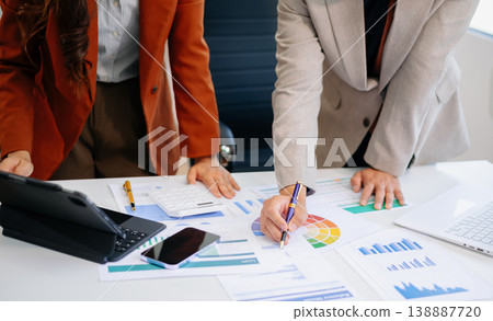 wo professionals collaborating on color schemes and marketing strategy using a color wheel and printed analytics. wo professionals collaborating on color schemes and marketing strategy using a color wheel and printed analytics. 138887720