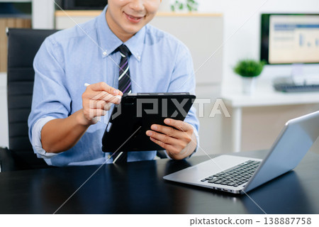 Confident businessman working on laptop, tablet and smartphone at her workplace in office 138887758