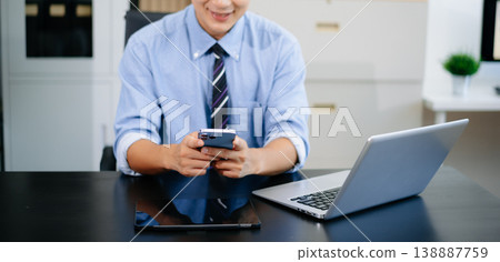 Confident businessman working on laptop, tablet and smartphone at her workplace in office Confident businessman working on laptop, tablet and smartphone at her workplace in office 138887759