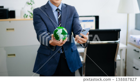 Asian business team discussing sustainable strategy while holding a globe model. Perfect for themes like eco business, green planning, environmental responsibility Asian business team discussing sustainable strategy while holding a globe model. Perfect for themes like eco business, green planning, environmental responsibility 138887827