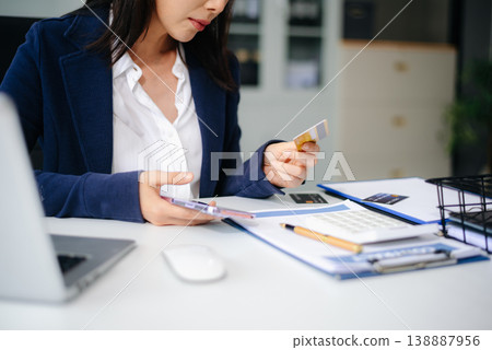 Stressed Asian businesswoman holding multiple credit cards in office, facing financial pressure. Stressed Asian businesswoman holding multiple credit cards in office, facing financial pressure. 138887956