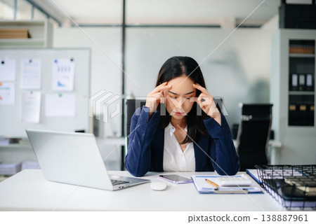 Asian businesswoman showing stress and frustration at office desk with laptop and calculator. Real people, financial pressure, work overload, deadline stress, burnout concept. Asian businesswoman showing stress and frustration at office desk with laptop and calculator. Real people, financial pressure, work overload, deadline stress, burnout concept. 138887961