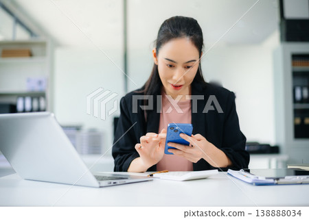 Confident Asian businesswoman using tablet in modern office with laptop and documents, showcasing finance, remote work Confident Asian businesswoman using tablet in modern office with laptop and documents, showcasing finance, remote work 138888034