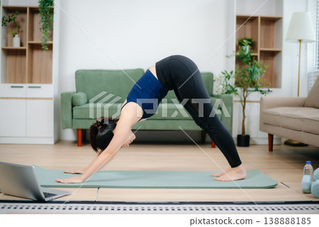 Young Asian woman practicing yoga indoors on a mat. Calm, healthy lifestyle, stretching, wellness and fitness at home Young Asian woman practicing yoga indoors on a mat. Calm, healthy lifestyle, stretching, wellness and fitness at home 138888185