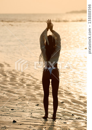 A beautiful tanned girl in a swimsuit stands along a white beach at sunset in the Maldives, she is happy, posing for a photographer A beautiful tanned girl in a swimsuit stands along a white beach at sunset in the Maldives, she is happy, posing for a photographer 138888566