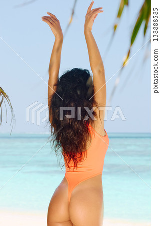 A beautiful tanned girl is wearing in orange swimsuit fun on the personal beach of the villa on a sunny day in the Maldives, she is happy and posing 138888585