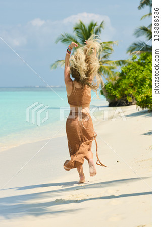 A beautiful tanned girl with an athletic physique in a swimsuit runs on the personal beach of the villa on a sunny day in the Maldives, she is happy and posing 138888586