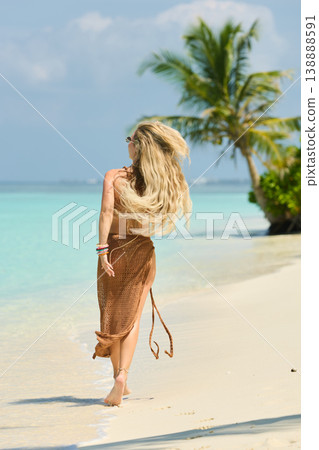 A beautiful tanned girl with an athletic physique in a swimsuit runs on the personal beach of the villa on a sunny day in the Maldives, she is happy and posing 138888591