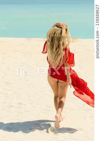 A beautiful tanned girl is wearing in red cape fun on the personal beach of the villa on a sunny day in the Maldives, she is happy and posing A beautiful tanned girl is wearing in red cape fun on the personal beach of the villa on a sunny day in the Maldives, she is happy and posing 138888627